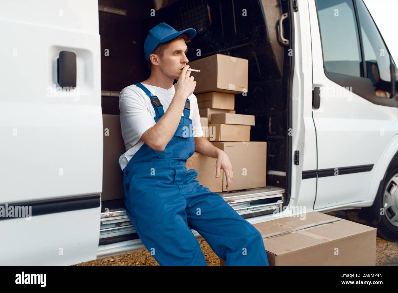 Deliveryman raucht am Auto während einer Pause Stockfoto