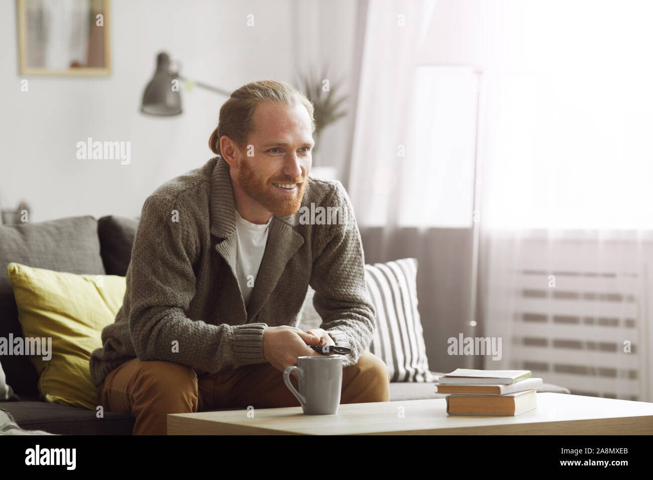 Portrait von lächelnden bärtiger Mann vor dem Fernseher zu Hause und Fernbedienung, kopieren Raum Stockfoto