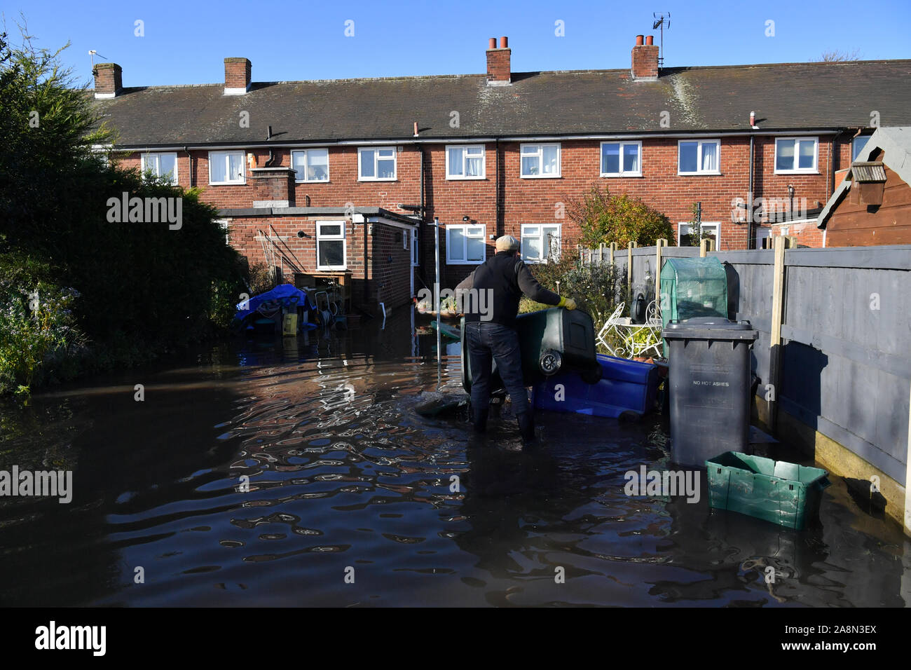 Ein Mann leert Bins floodwater Kontamination in Fishlake, Doncaster zu vermeiden, die als Teile von England von einem Monat im Wert von Regen in 24 Stunden ausgehalten, mit Kerben von Menschen gerettet oder gezwungen, ihre Häuser zu verlassen. Stockfoto