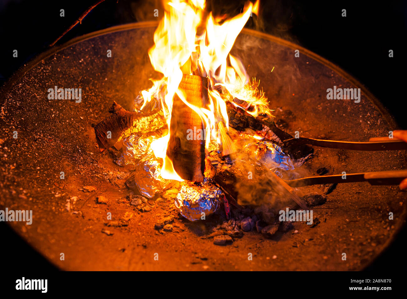 Kartoffeln eingewickelt in Alufolie gebacken in einem Lagerfeuer. Stockfoto