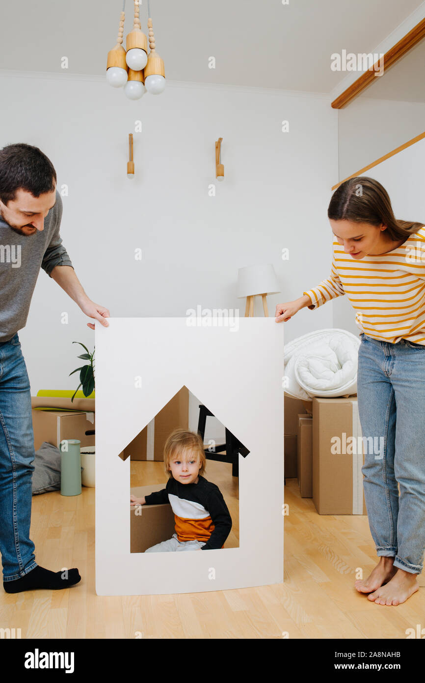 Kleiner Junge sitzt in einem Haus wie Rahmen, von seinen Eltern gehalten Stockfoto