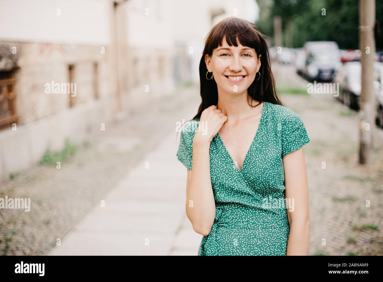 Frau mit einem eleganten grünen Kleid lächelt in die Kamera Stockfoto