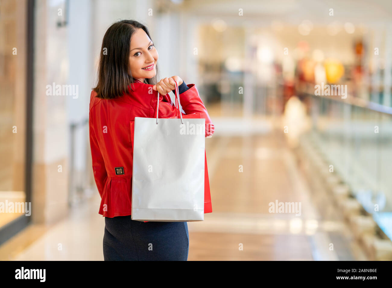 Junge Frau ist zu Fuß in einer Mall und ist Einkaufen mit einem glücklichen Lächeln. Stockfoto