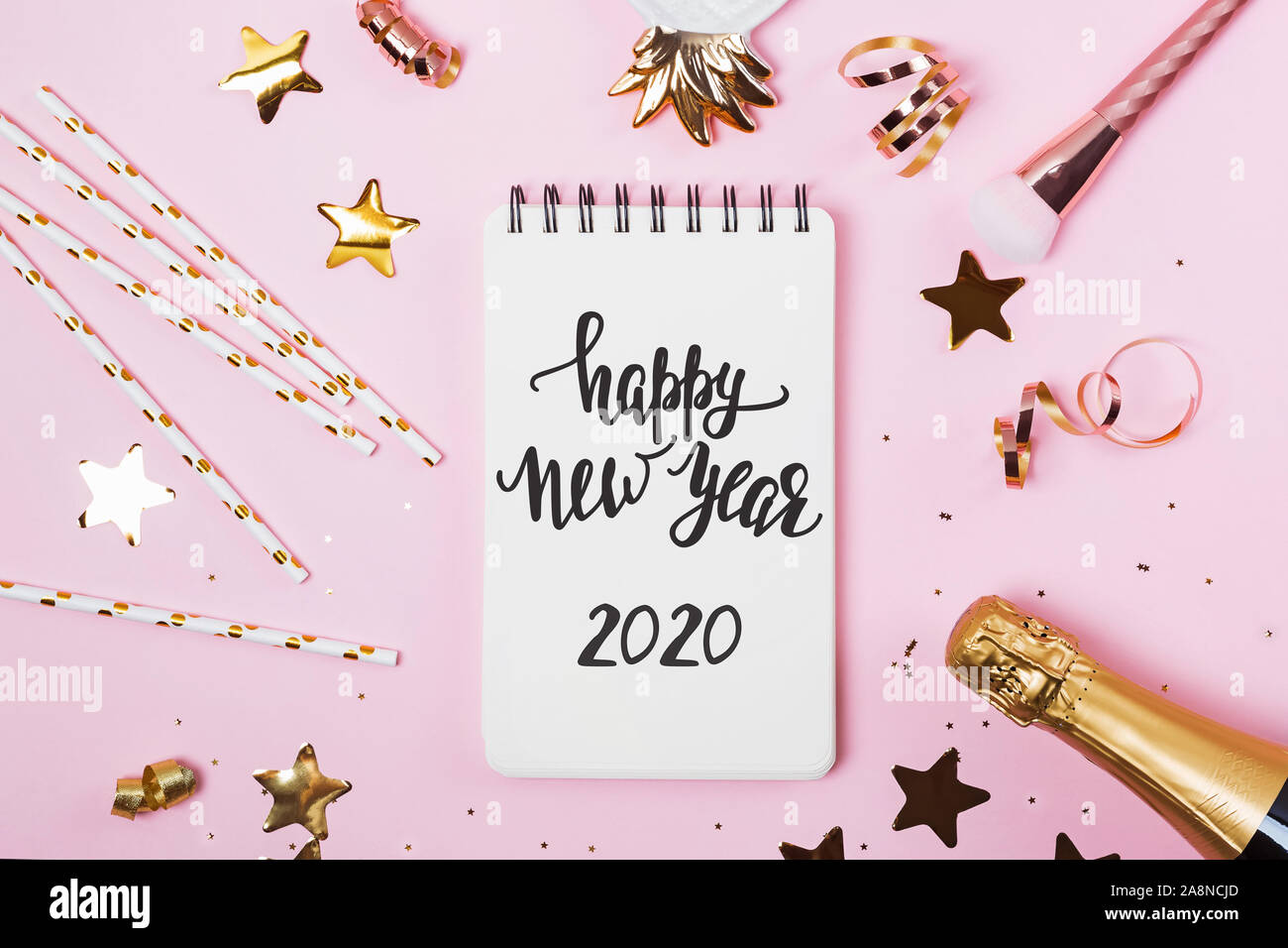 Notizblock mit mit Text ein Frohes Neues Jahr 2020 auf rosa Hintergrund mit goldenen Konfetti, Glitter und andere Stockfoto