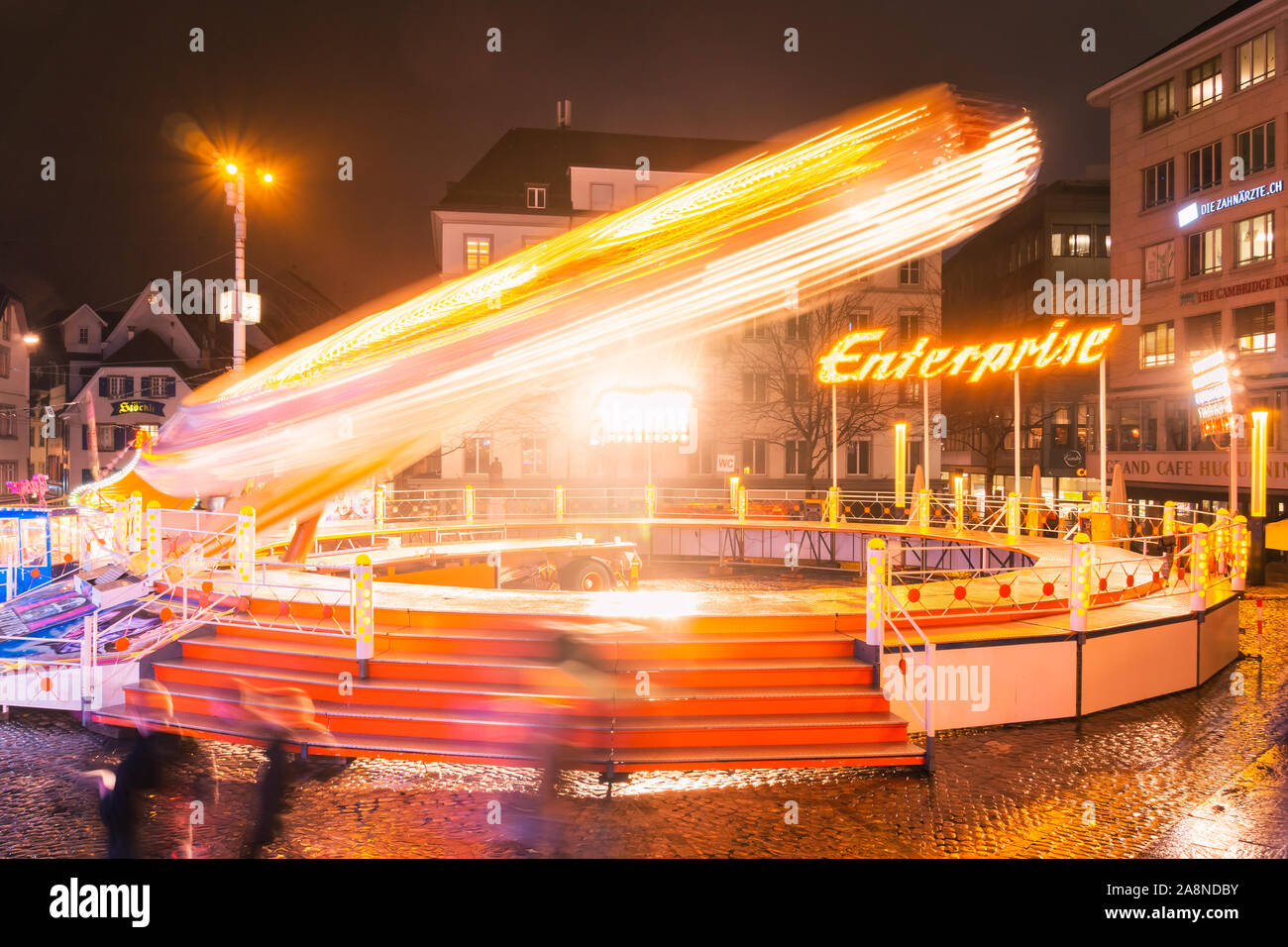Die Enterprise Fahrgeschäft in Bewegung mit dem Rad, die Spinnen sehr schnelle, Reisen kirmes Herbst Messe in der Nacht in der Innenstadt von Basel, Schweiz. Stockfoto