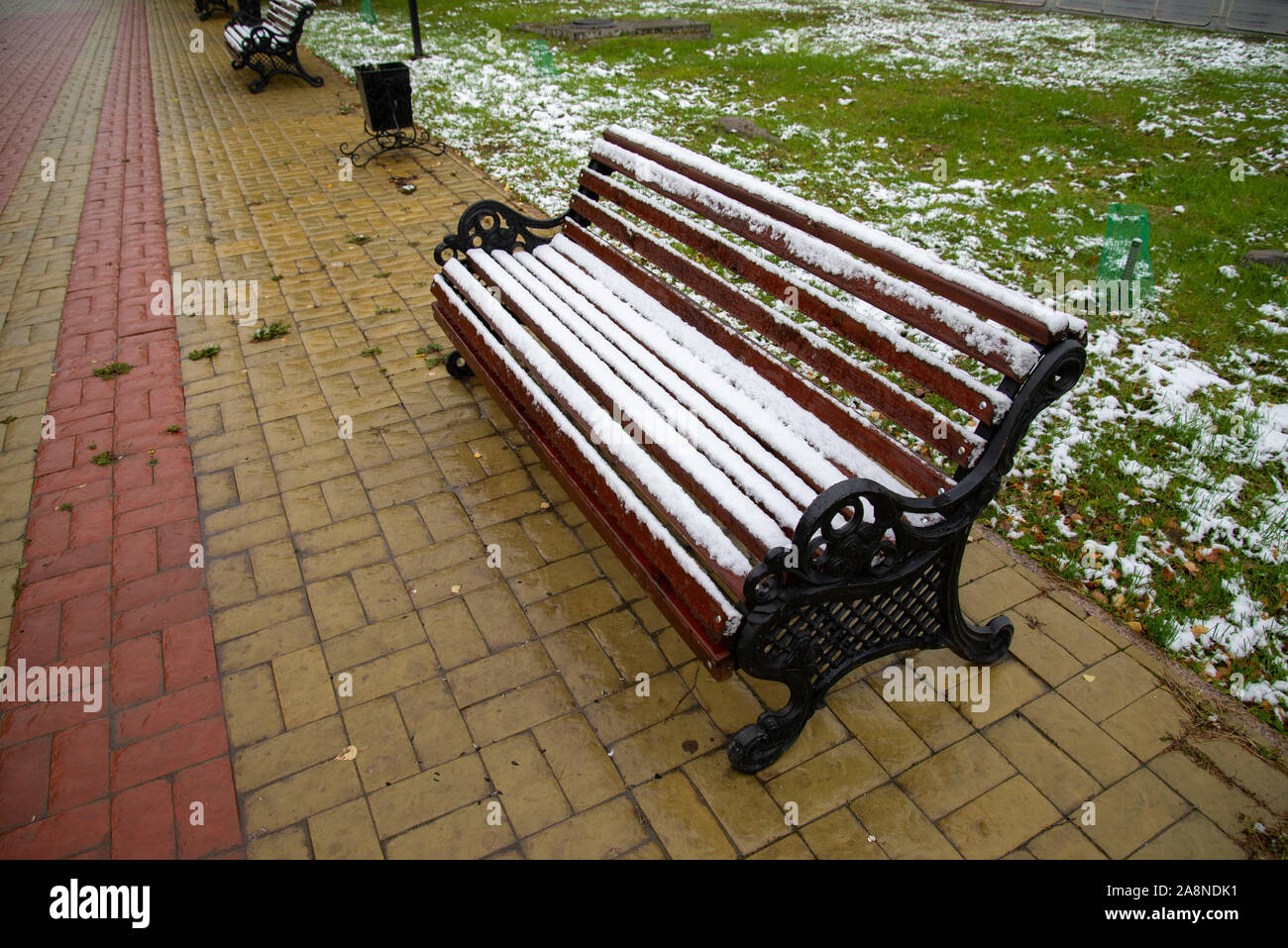 Verschneite Bank für die Entspannung in den Park auf der Aussichtsplattform. Herbst, der erste Schnee. Stockfoto