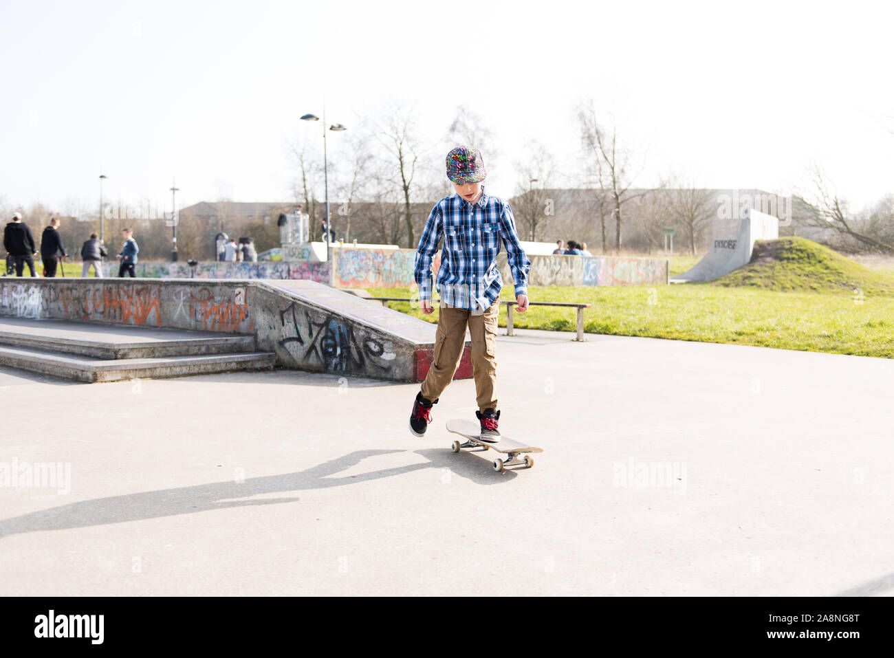 Einen kleinen Jungen mit ADHS, Autismus, Asperger-syndrom Üben seines Skateboarder im lokalen Skatepark, energisch und zielstrebig, Skater, Musik Stockfoto