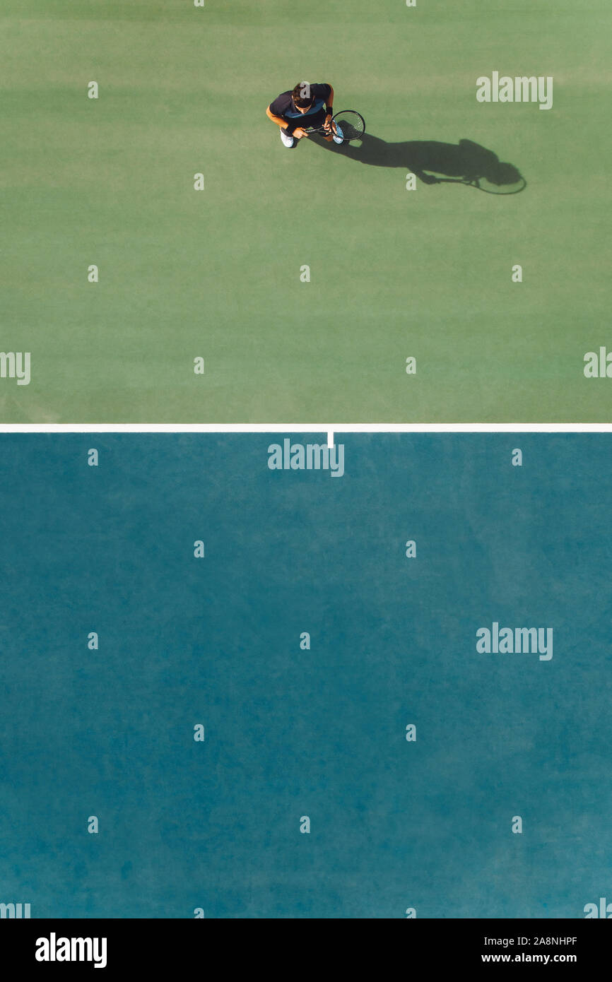 Luftaufnahme von jungen männlichen Tennisspieler stehen auf Hartplatz. Professional tennis player auf hartplatz. Stockfoto