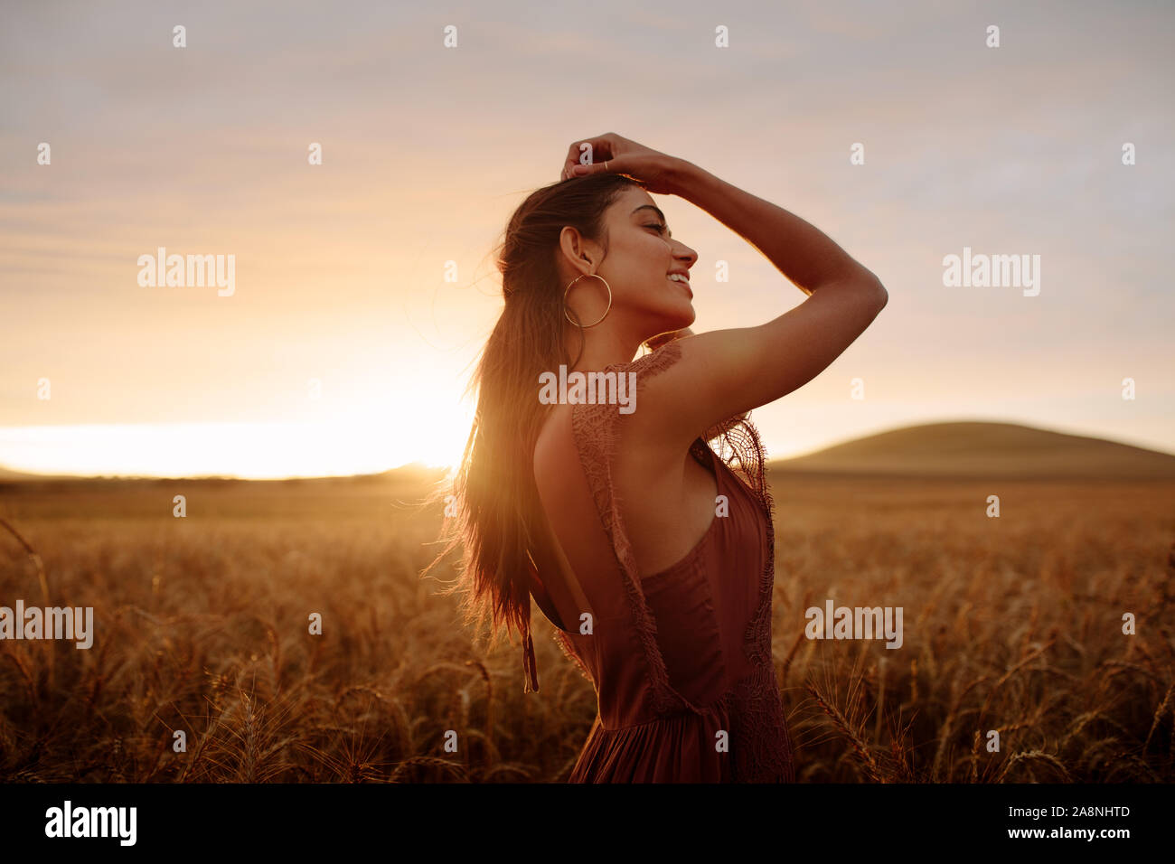 Junge Frau in einem Feld während der Dämmerung. Weibliche genießen Sie einen Tag in der Natur bei Sonnenuntergang. Stockfoto
