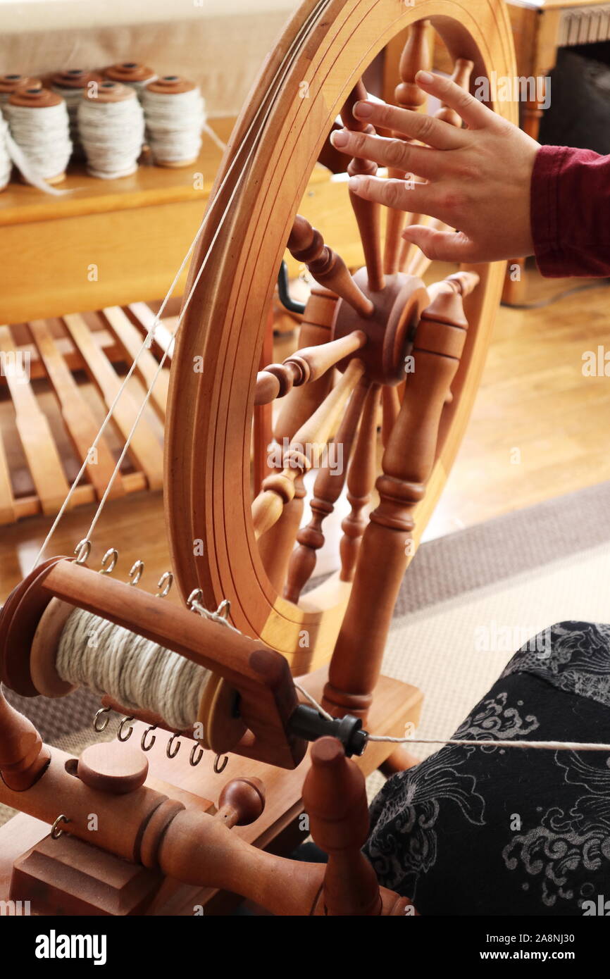 Jungfer (Person, die Garn macht) sitzen an einem großen, doppelt fahren, Sachsen Spinnrad erstellen Hellgrau Garn Stockfoto