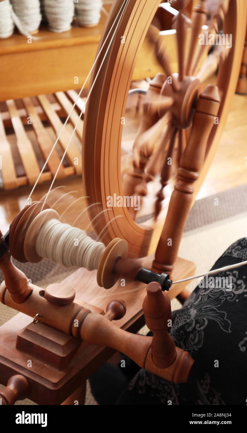 Jungfer (Person, die Garn macht) sitzen an einem großen, doppelt fahren, Sachsen Spinnrad erstellen Hellgrau Garn Stockfoto