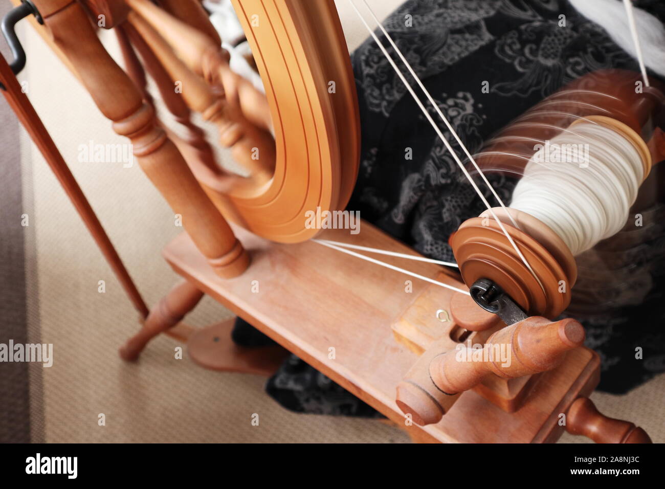 Jungfer (Person, die Garn macht) sitzen an einem großen, doppelt fahren, Sachsen Spinnrad erstellen Hellgrau Garn Stockfoto