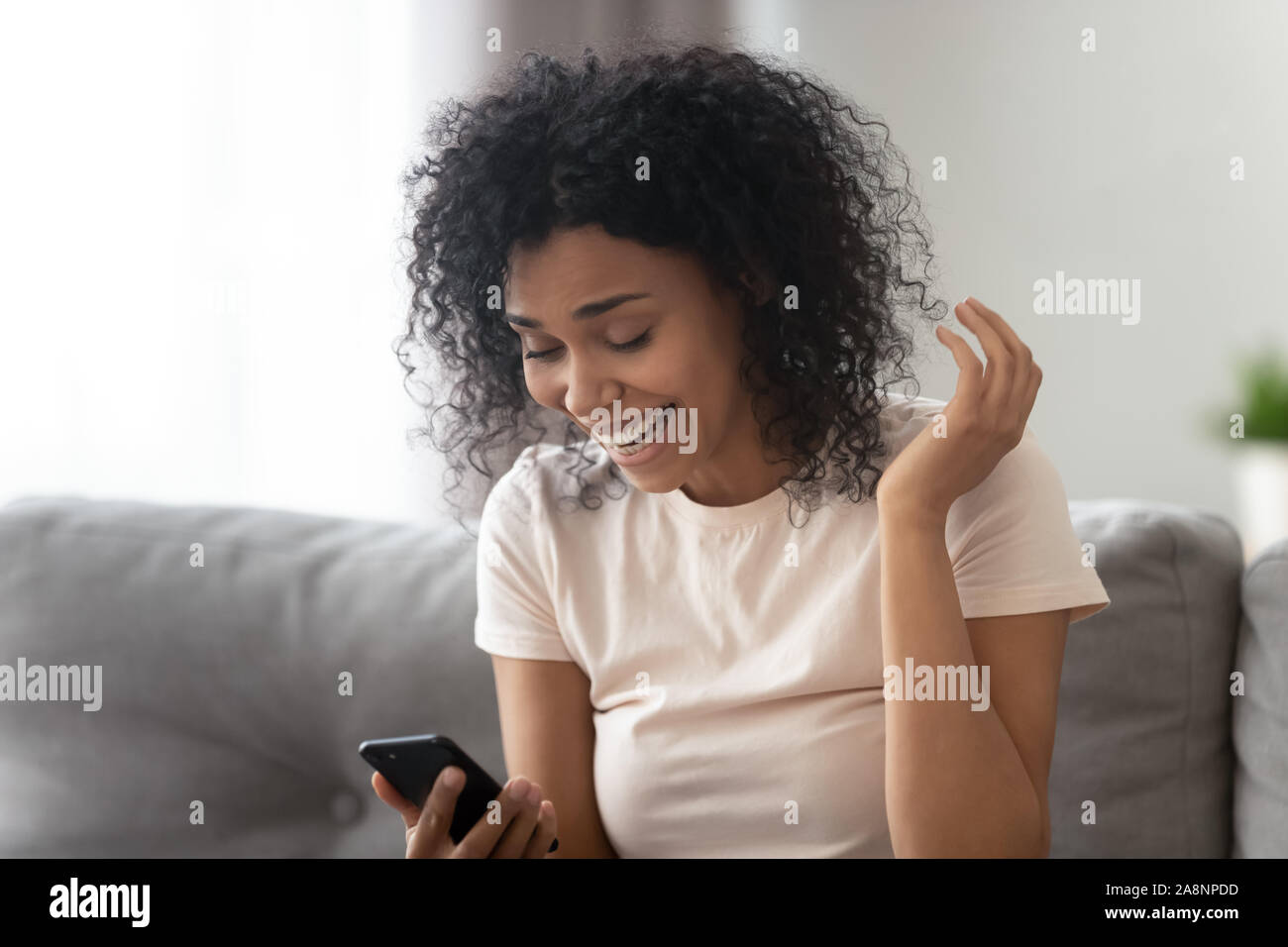 Überrascht African American Woman Reading unerwartet gute Nachrichten über das Telefon Stockfoto