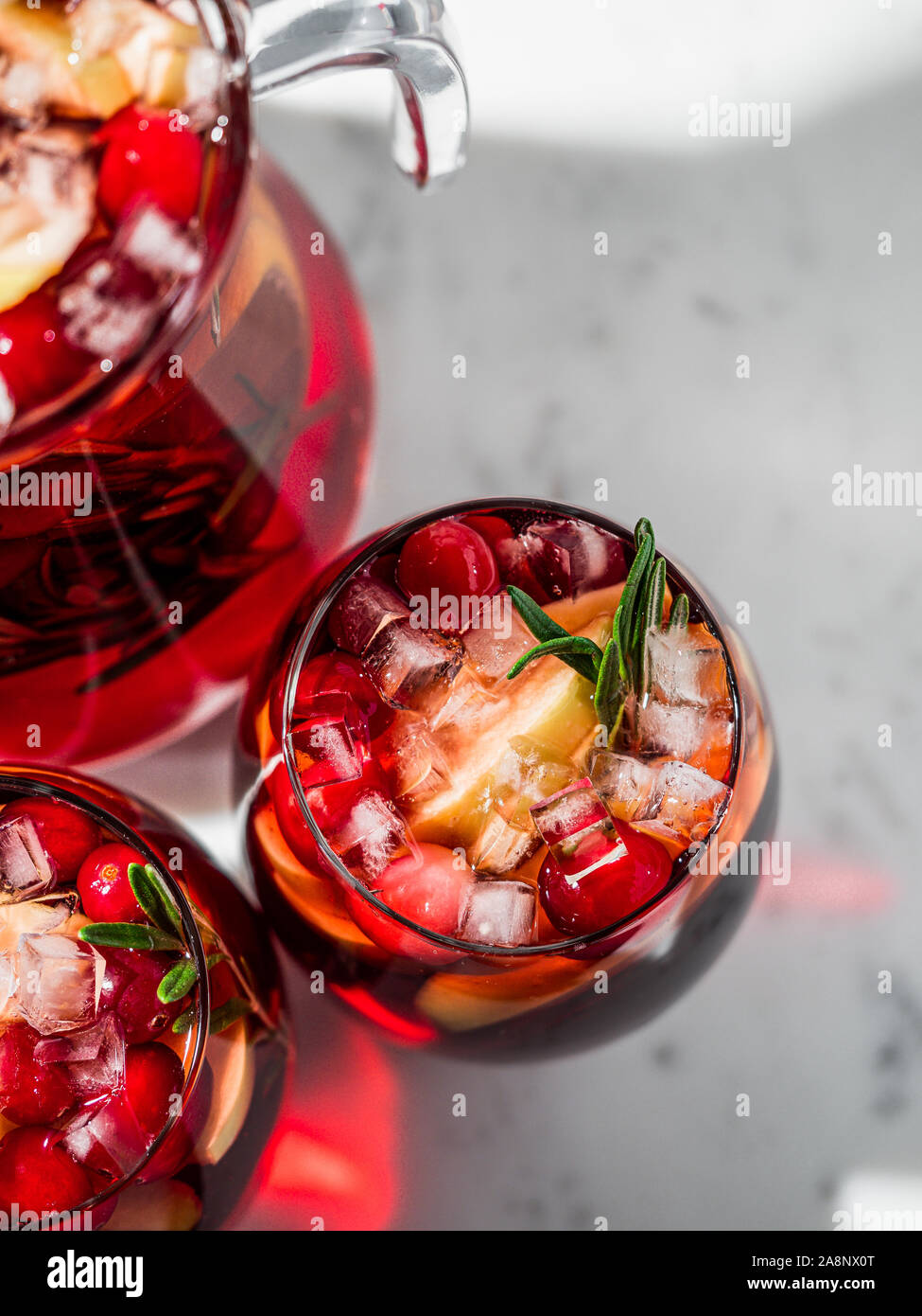 Winter Sangria auf der Tischplatte mit grau Leinen Tischdecke. Gläser Sangria mit Obst schneiden, Cranberry und Rosmarin. Kopieren Sie Platz für Text oder Design. Top View oder flach. Vertikale. Stockfoto