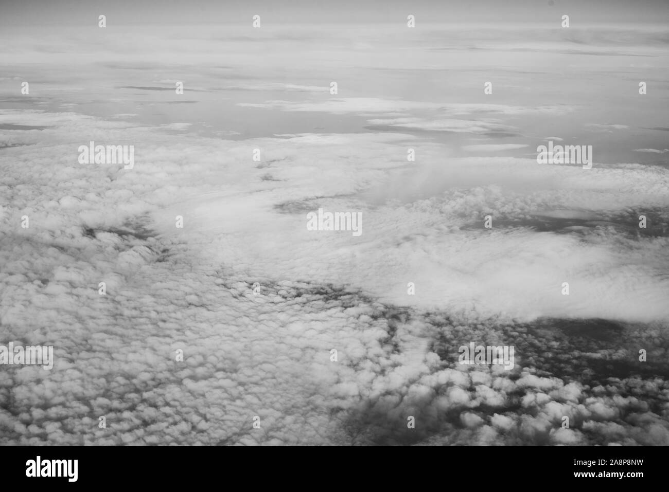 Flauschigen weißen Wolken Ansicht von oben aus dem Flugzeug Fenster. Schwarz und Weiß Foto Stockfoto