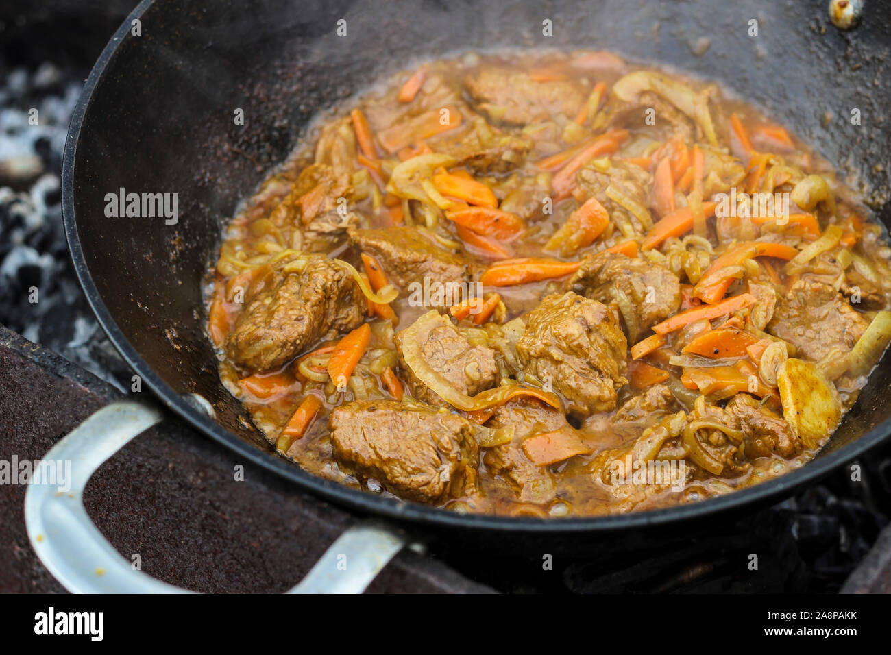 Stücke von Fleisch sind in einem Kessel auf Feuer gebraten Stockfoto