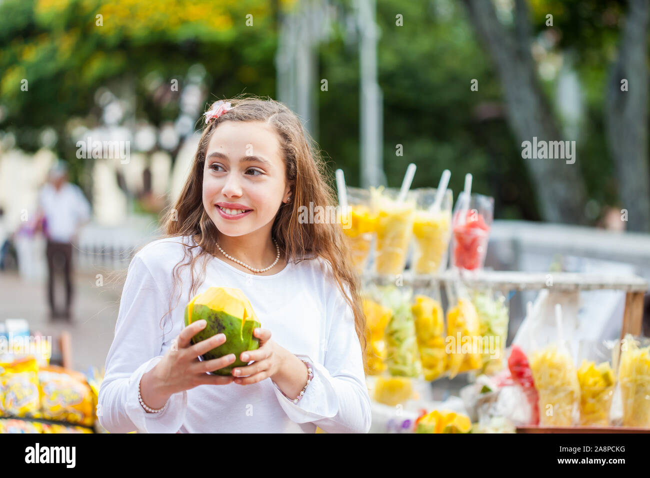 Schöne junge Mädchen am Paseo Bolivar Square in der Stadt Cali Essen tropische Früchte in Kolumbien Stockfoto