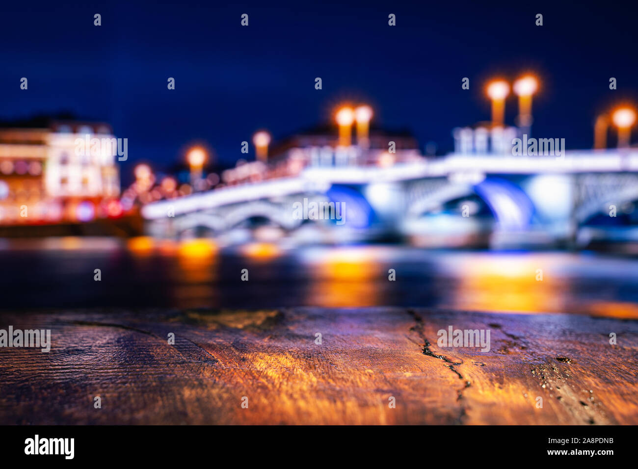 Leere Holztisch mit Blick verschwommene Abend Stadt. Hintergrund für die Produktplatzierung Stockfoto
