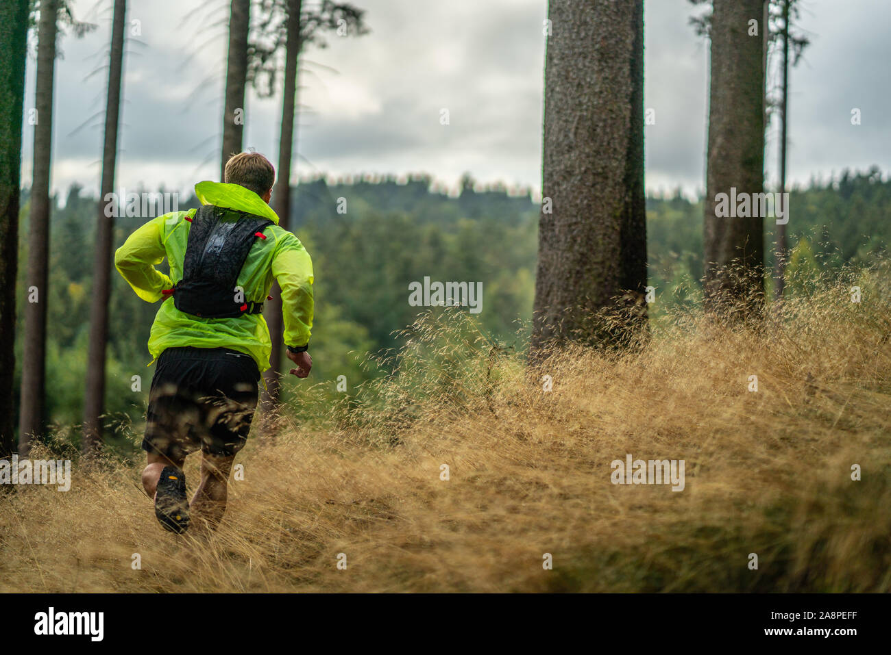 Ein junger Athlet in Barfuß Schuhe läuft den Berg hinauf. Die Berge laufen. Querfeldein laufen. Einzelnen Sport Stockfoto