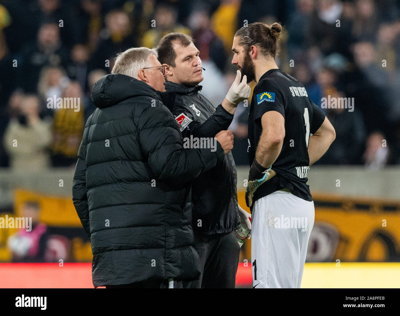 Dresden, Deutschland. 08 Nov, 2019. 2. Fussball Bundesliga, SG Dynamo Dresden - SV Wehen Wiesbaden, 13.Spieltag, im Rudolf Harbig Stadion. Der Wiesbadener Torwart Lukas Watkowiak (r) ist auf dem Ohr nach einem knallkörper Wurf aus dem Dresdner fan Block behandelt. Credit: Robert Michael/dpa-Zentralbild/dpa - WICHTIGER HINWEIS: In Übereinstimmung mit den Anforderungen der DFL Deutsche Fußball Liga oder der DFB Deutscher Fußball-Bund ist es untersagt, zu verwenden oder verwendet Fotos im Stadion und/oder das Spiel in Form von Bildern und/oder Videos - wie Foto Sequenzen getroffen haben./dpa/Alamy leben Nachrichten Stockfoto