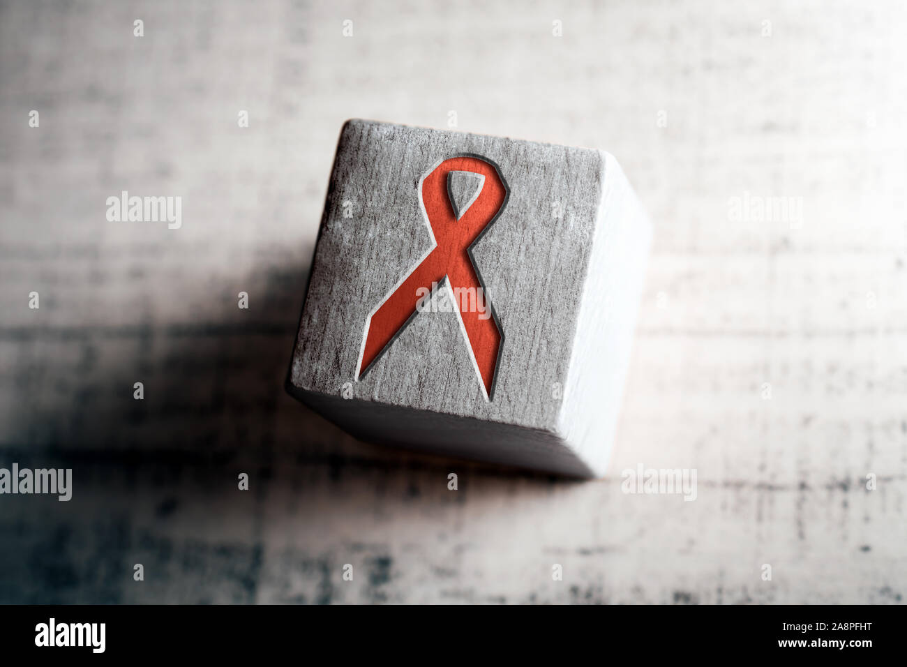 Rote AIDS und HIV Band auf hölzernen Block auf einem Tisch Stockfoto