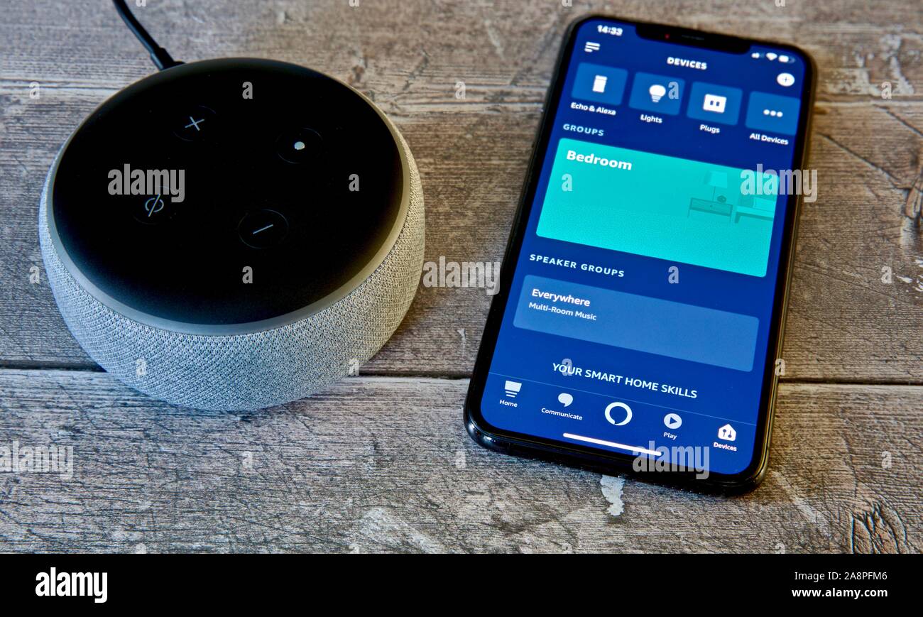 Amazon Echo Dot (3. Generation) Neben einem iPhone 11 zeigt die Alexa app Stockfoto