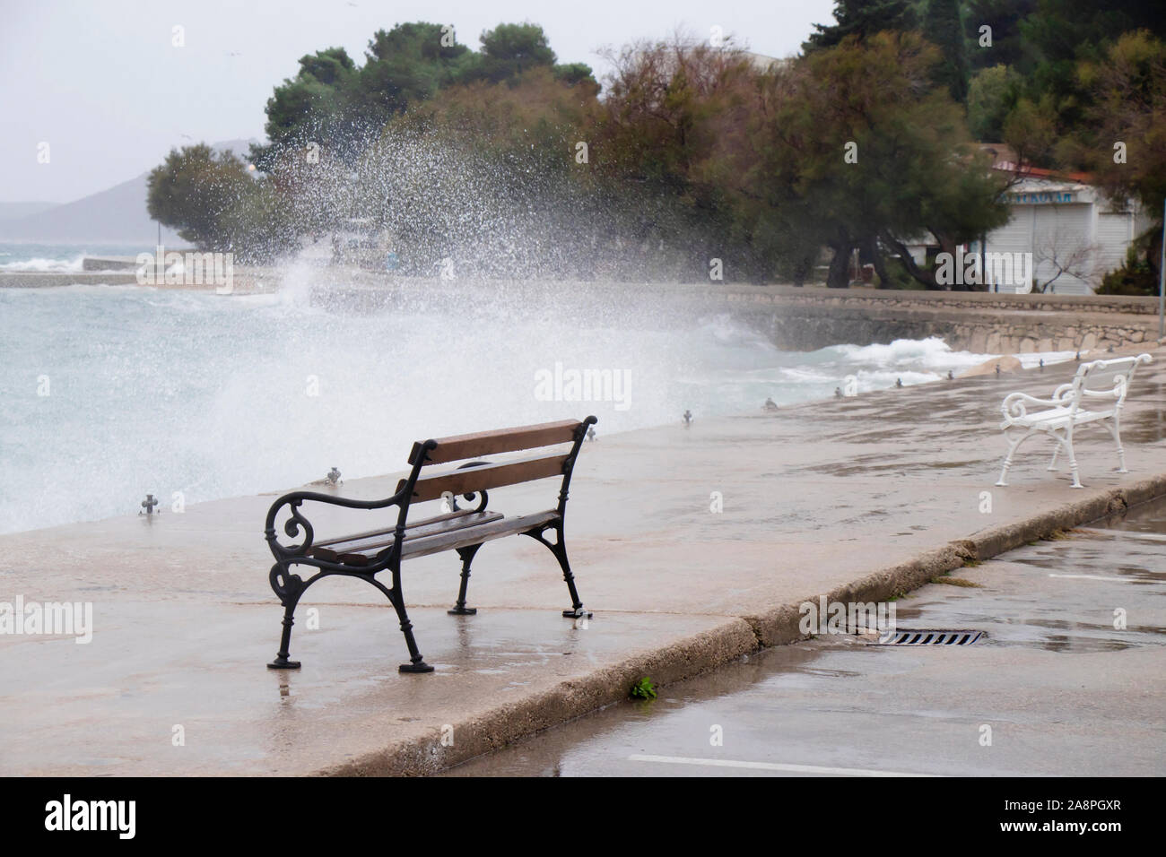 Leere Bänke von der Stürmischen See von den Wellen in Dalmatien Stadt am Meer in der Nebensaison spritzte bei starkem Südwind Stockfoto