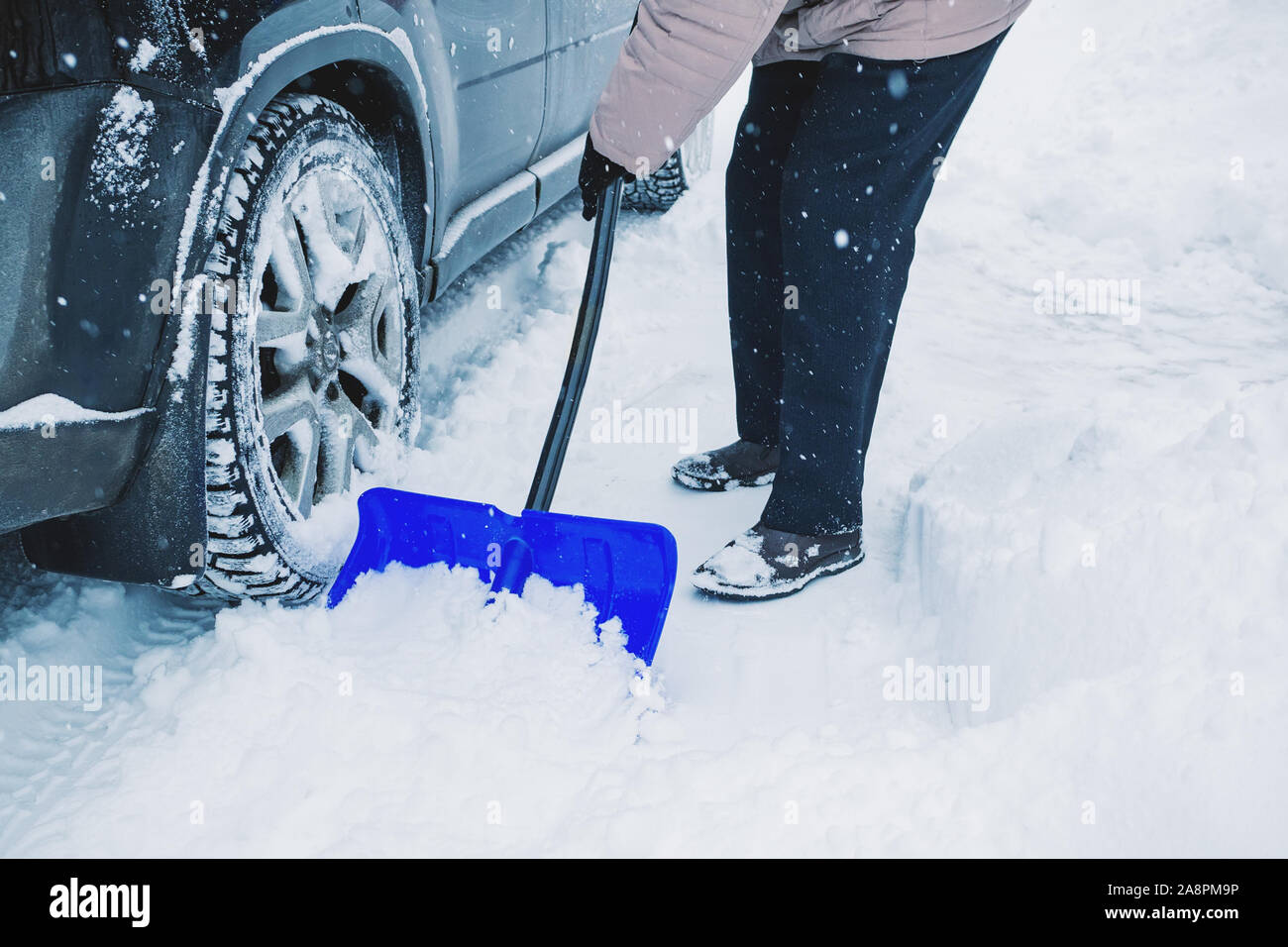 Hände von einem Mann, der das Auto reinigt und entfernt Schnee auf der Straße nach einem Schneesturm. Reinigung der Straßen der Stadt nach dem Schneefall. Stockfoto