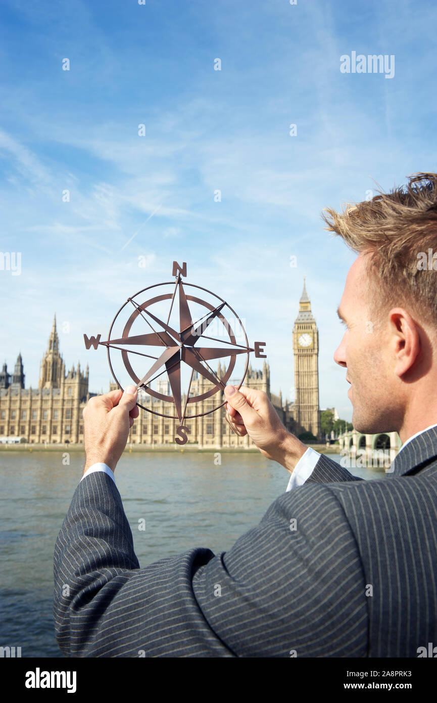 Geschäftsmann Holding altmodische Kompass, vor den Häusern des Parlaments, London, UK rose Stockfoto