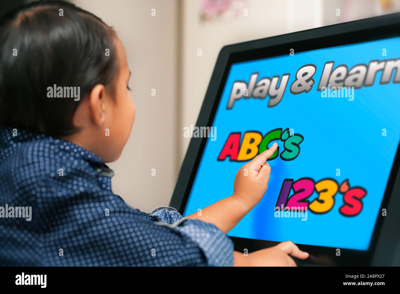 Ein kleines Kind an einem Touchscreen suchen und mit seinem Zeigefinger seiner ABC und Zahlen zu lernen. Stockfoto