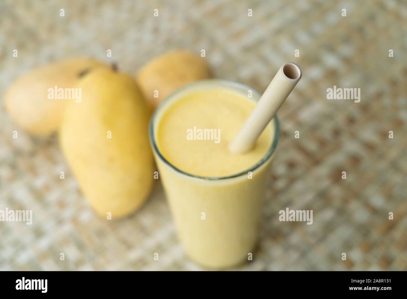 Ein Glas gefüllt mit Mango Smoothie und eine wieder verwendbare Bambus Strohhalm zum Trinken verwendet. Highlights die Möglichkeit, mit natürlichen Produkten als Alternative Stockfoto