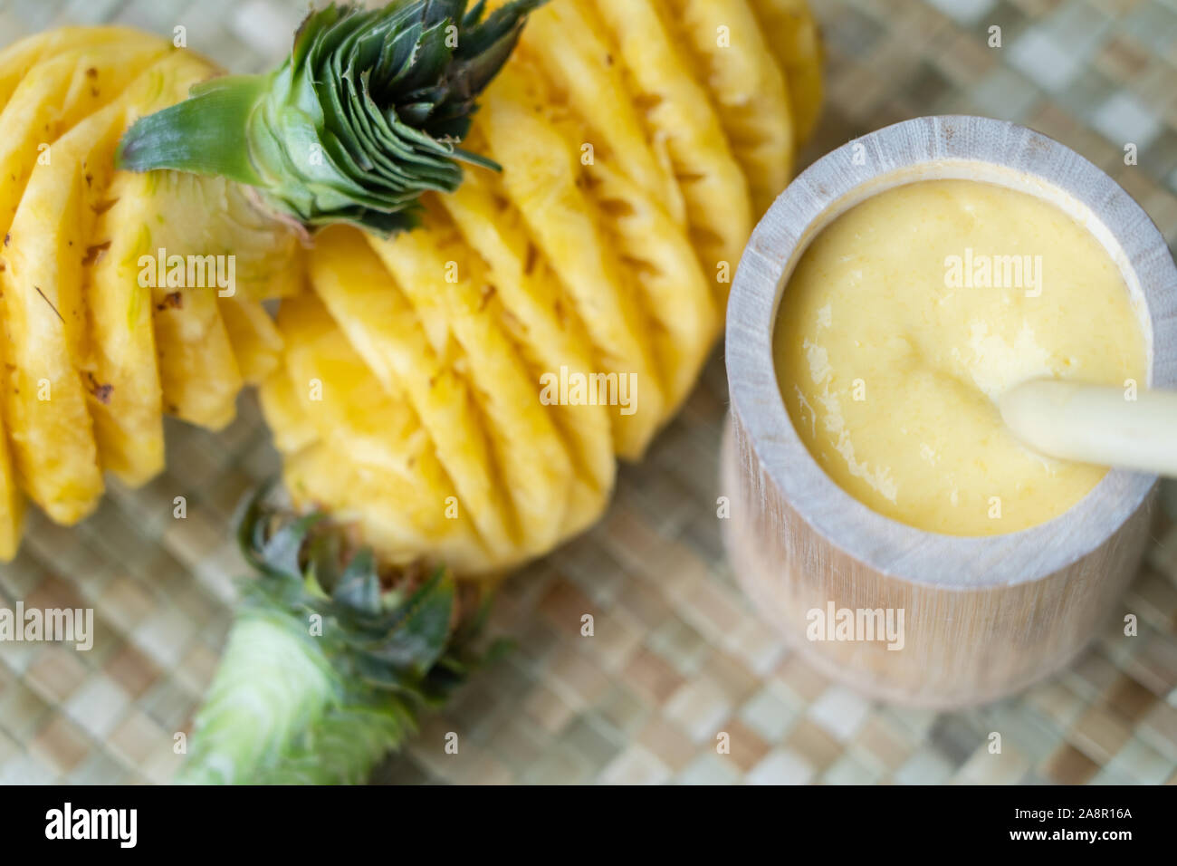 Eine einfache Schale aus Bambus gefüllt mit einer Ananas Smoothie und eine wieder verwendbare Bambus Strohhalm zum Trinken verwendet. Hebt die Möglichkeit der Verwendung von Nat Stockfoto