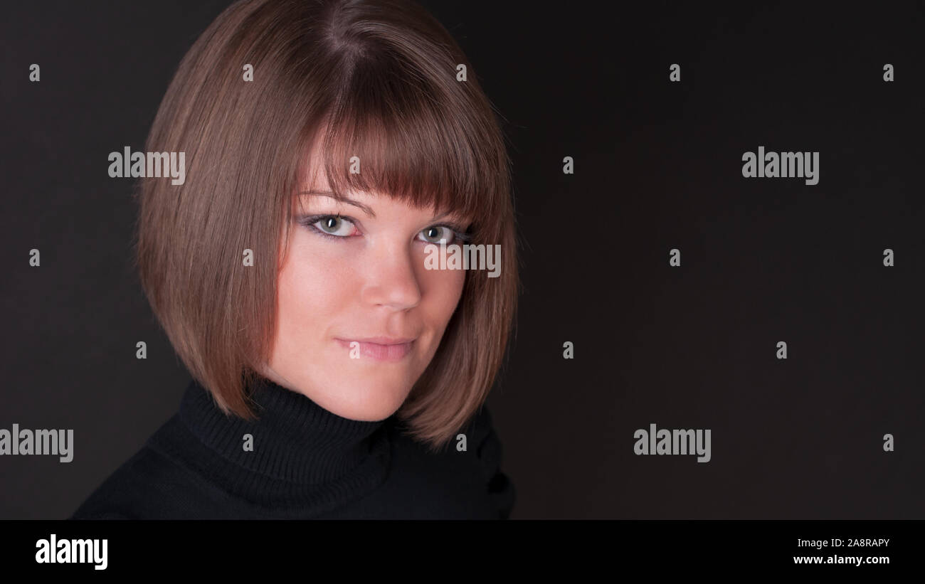 Porträt der hübsche junge Frau mit modernen Frisur auf schwarzem Hintergrund Stockfoto