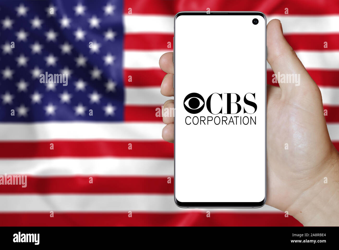 Logo der öffentlichen Unternehmen CBS Corp. auf dem Smartphone angezeigt. Flagge der USA Hintergrund. Credit: PIXDUCE Stockfoto