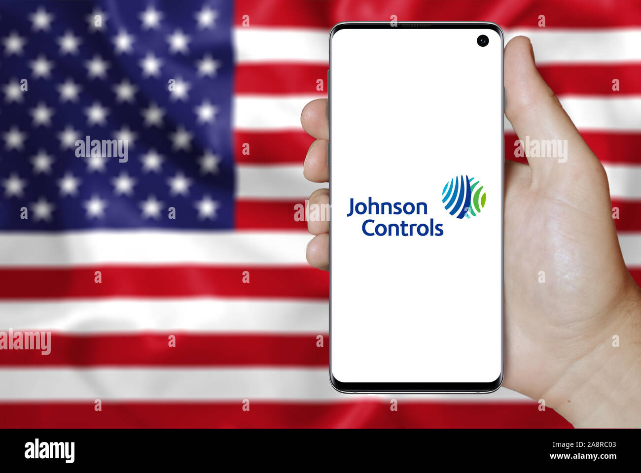 Logo der öffentlichen Unternehmen Johnson Controls International angezeigt auf einem Smartphone. Flagge der USA Hintergrund. Credit: PIXDUCE Stockfoto