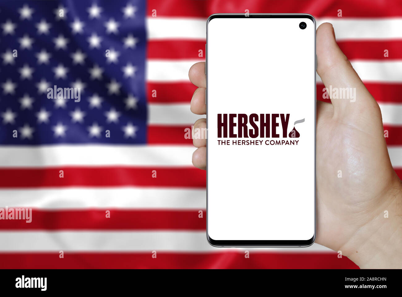 Logo der öffentlichen Unternehmen der Hershey Company auf einem Smartphone. Flagge der USA Hintergrund. Credit: PIXDUCE Stockfoto