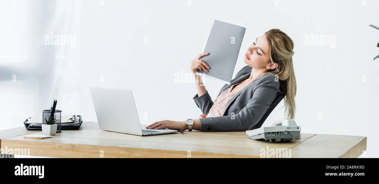 Panorama-aufnahme der Geschäftsfrau im Büro, Ordner in der Hand und Leiden von Wärme Stockfoto