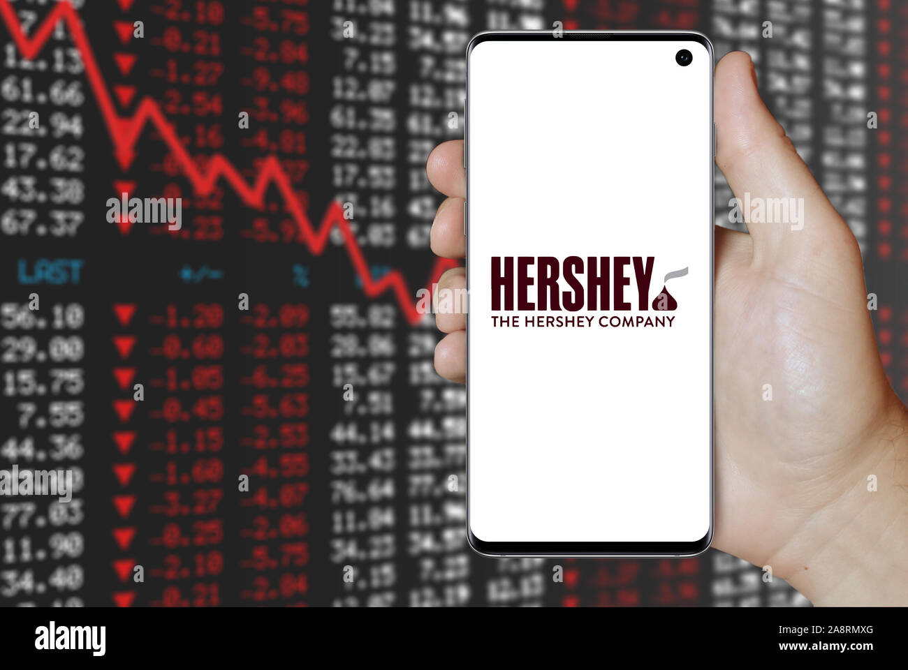 Logo der öffentlichen Unternehmen der Hershey Company auf einem Smartphone. Negative Börse Hintergrund. Credit: PIXDUCE Stockfoto
