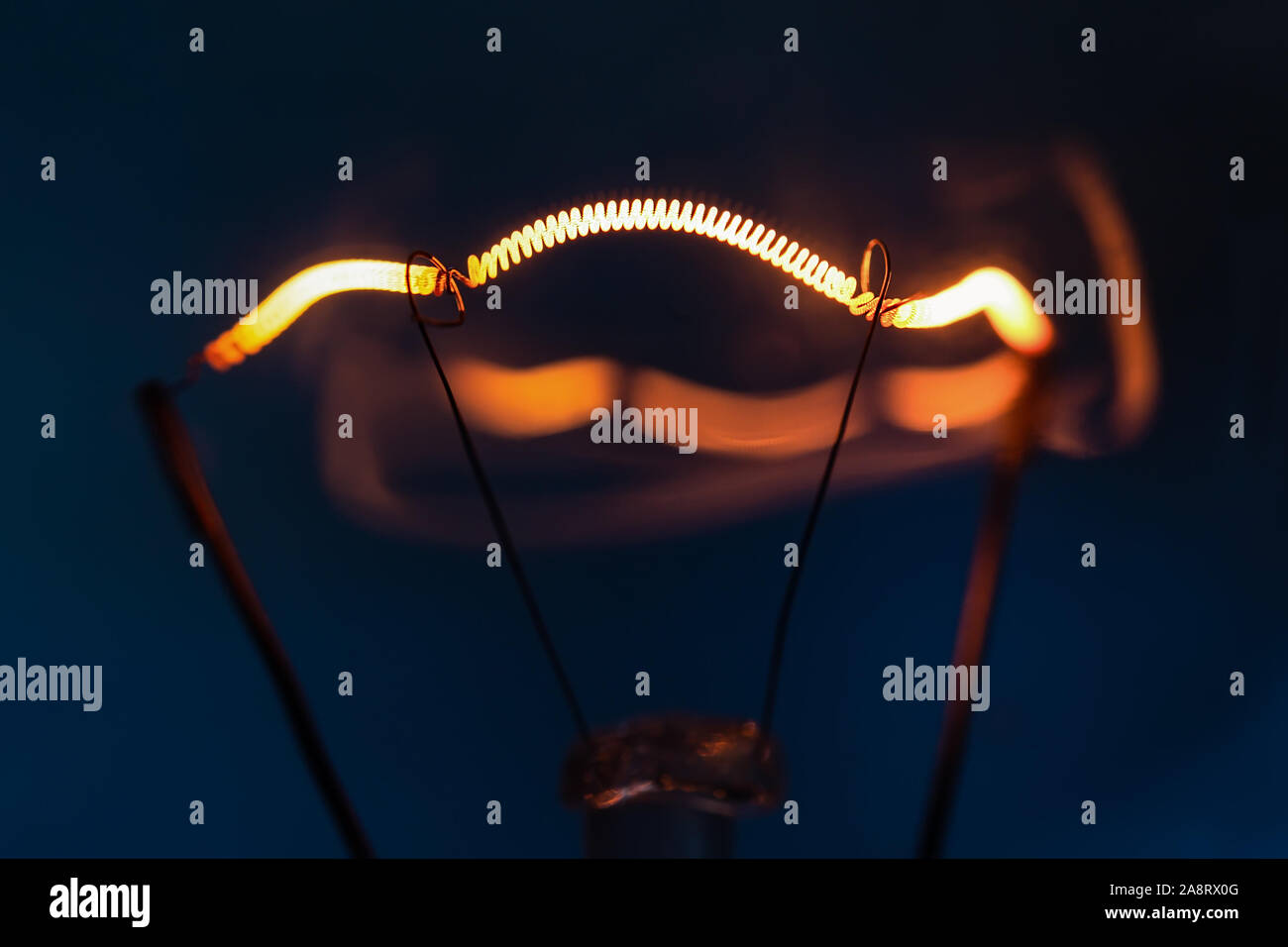 Leuchtende Glühlampe Glühlampe close-up auf dunkelblauem Hintergrund Stockfoto