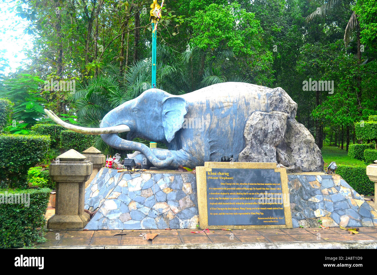 Ein Elefant Skulptur mit großen Stoßzähnen gemischt mit einem Felsen sitzen auf einer Mauer aus Stein mit einer placque in Jubilee Park Phang Nga Town Thailand Asien Stockfoto