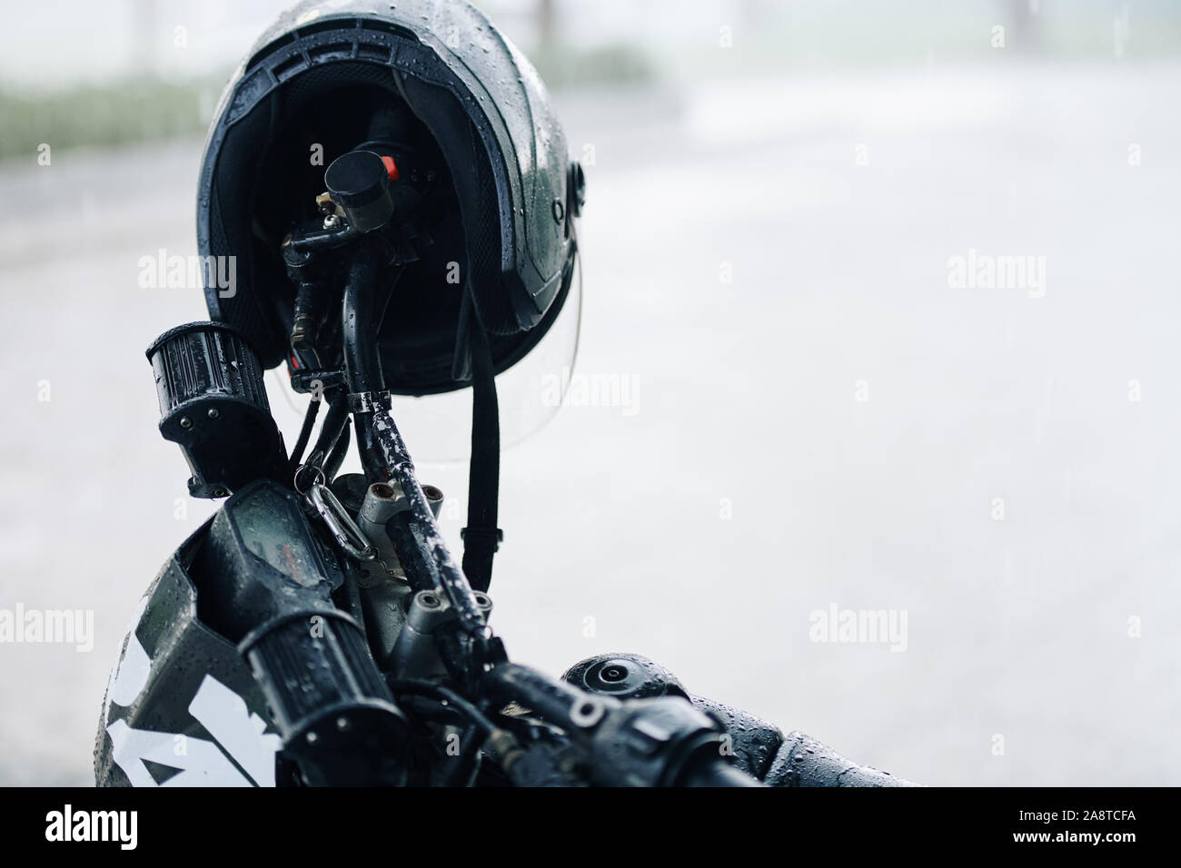 Nassen schwarzen Helm hängen am Lenker des Motorrades an regnerischen Tag Stockfoto