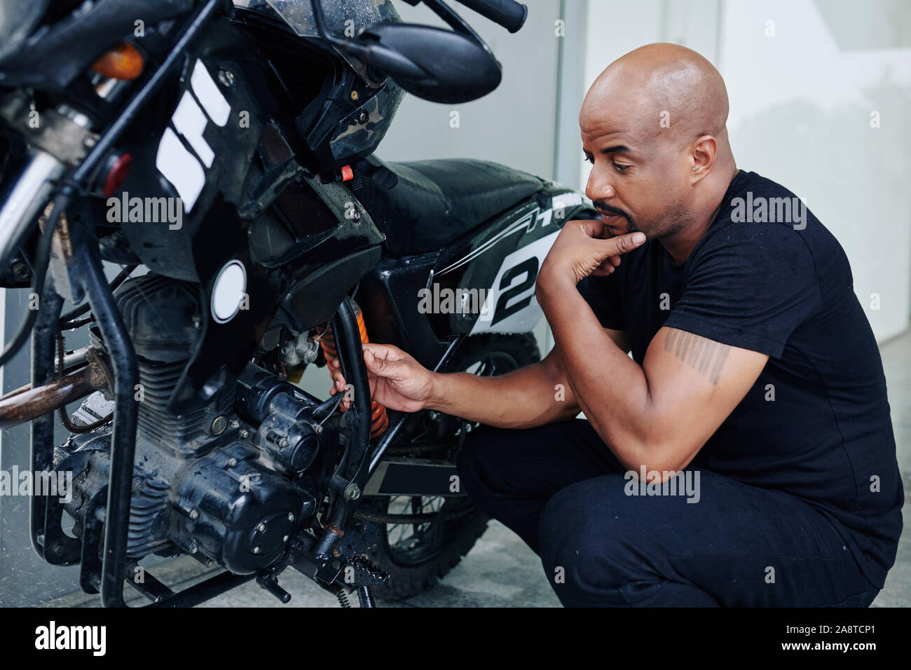 Nachdenklicher Mann am Motor von seinem Motorrad suchen und versuchen,  herauszufinden, warum es nicht funktioniert Stockfotografie - Alamy