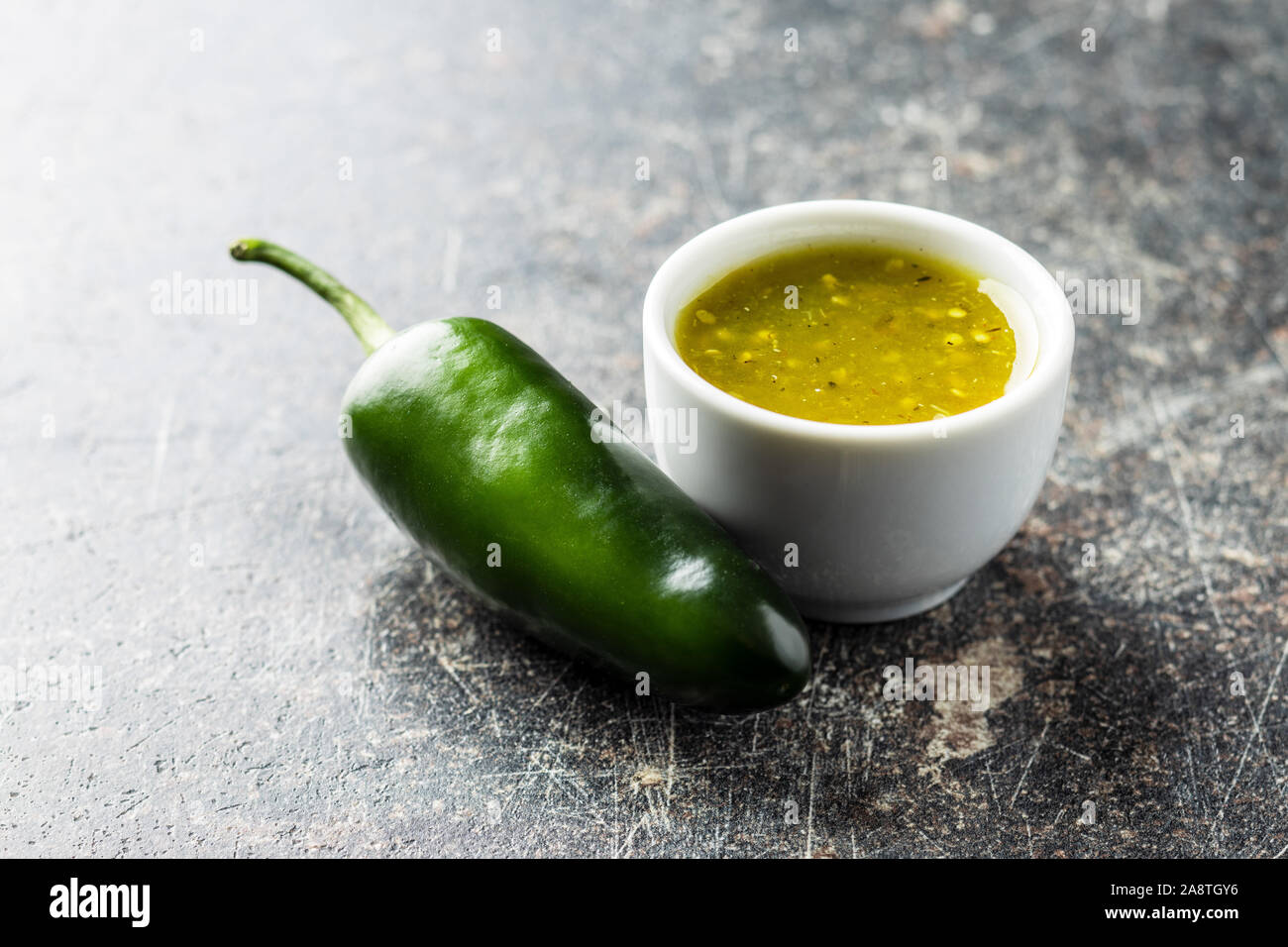 Grüne jalapeno Pfeffer und Tabasco Sauce auf alten Küchentisch. Stockfoto