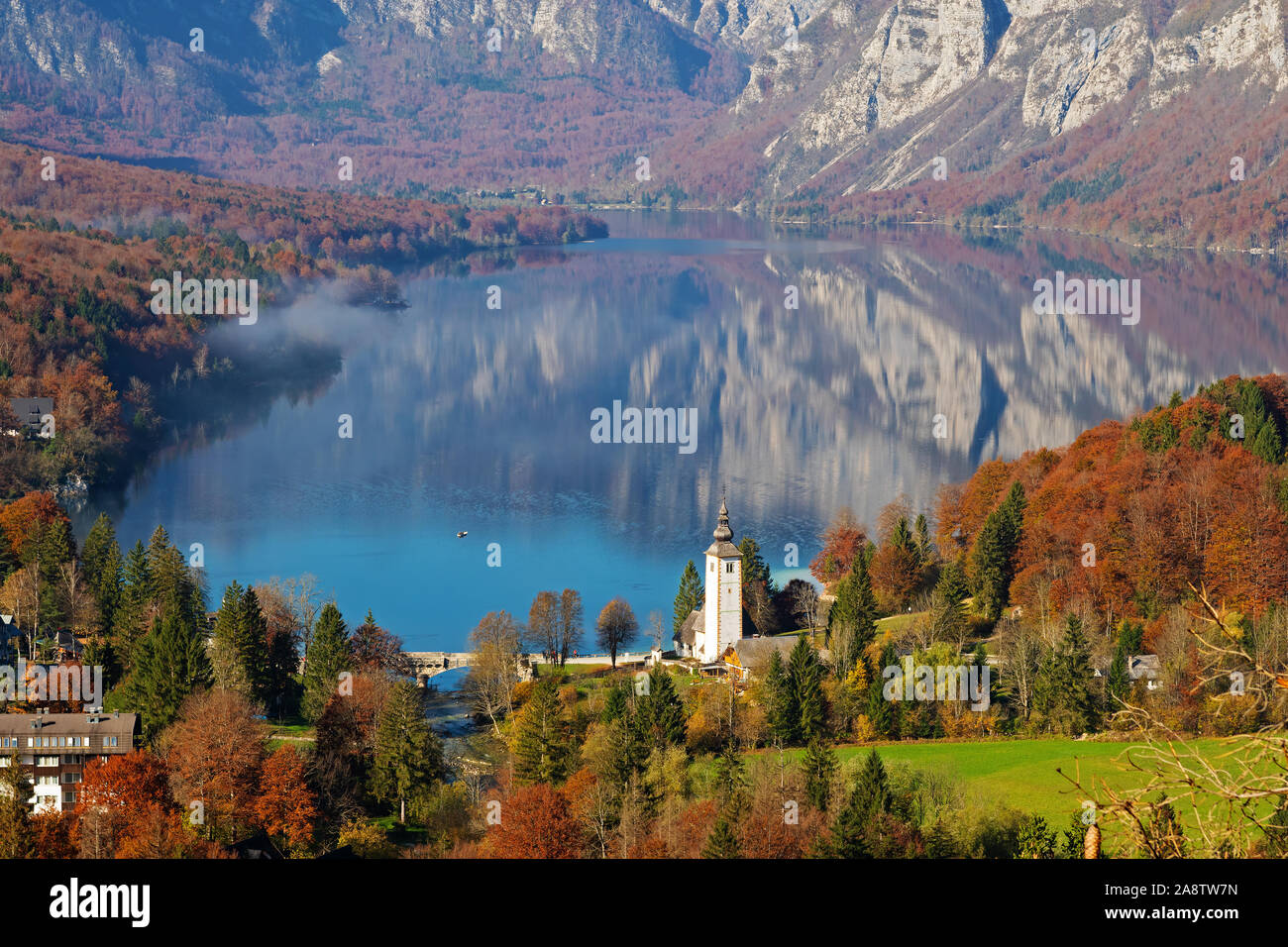 Herrliche Aussicht auf den See von Bohinj und der Kirche von Johannes dem Täufer in den Farben des Herbstes an einem sonnigen Morgen in Slowenien. Reisen, Tourismus und Schönheit Stockfoto
