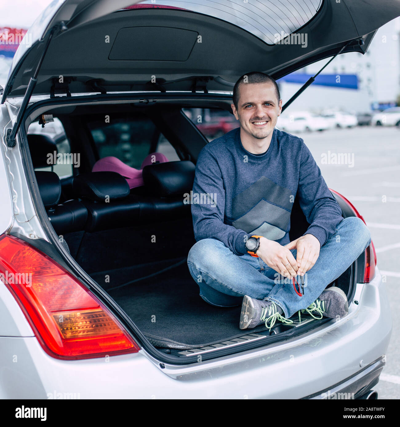 Mann lächelnd und schauen in die Kamera während der Sitzung im Kofferraum des Autos Stockfoto