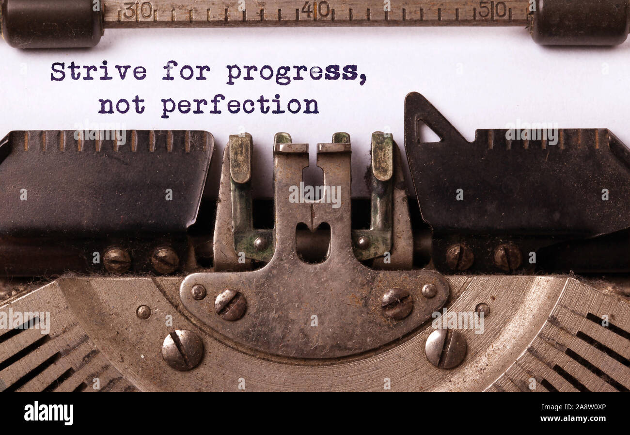 Streben nach Fortschritt, nicht Perfektion - auf einer alten Schreibmaschine geschrieben, vintage Stockfoto