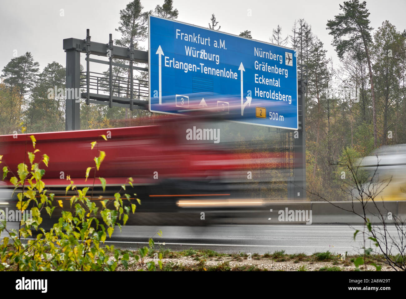 Lkw in verschwommene Bewegung entlang Wegweiser auf der Autobahn A3 fahren in Deutschland, die den Weg nach Frankfurt am Main, Würzburg, Erlangen und Nürnberg. Gesehen o Stockfoto