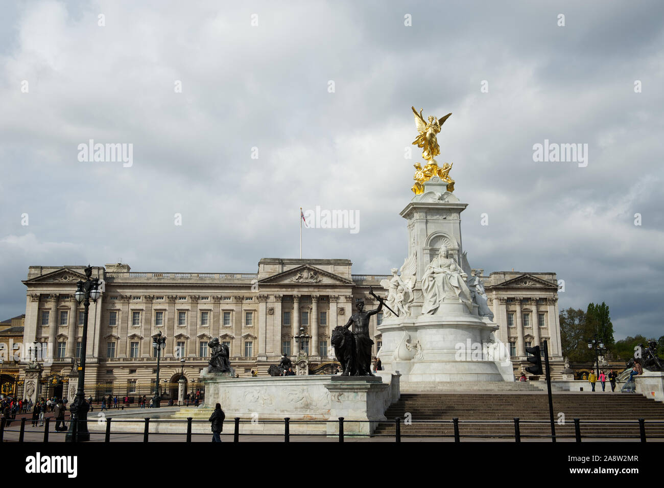 London - 7. MAI 2012: Grauer Himmel hängt über Fußgängern, die das Victoria Monument vor dem Buckingham Palace passieren. Stockfoto