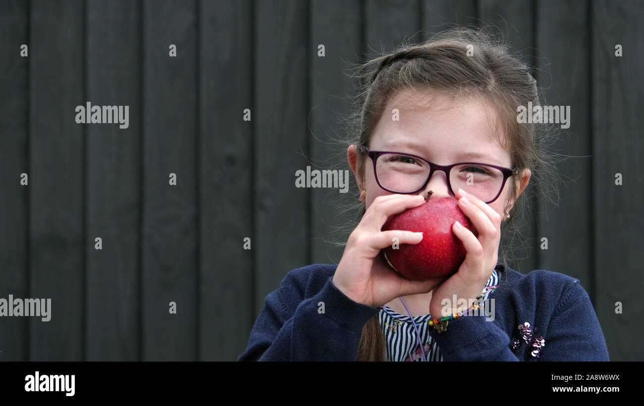 Ein junges Mädchen essen und genießen Sie die gesunden roten Apfel. Einer ihrer Frucht fünf ein Tag Stockfoto