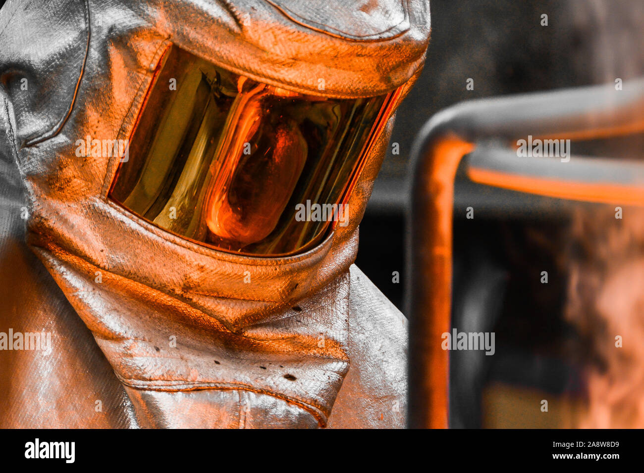 In einer Gießerei-Werkstatt. Das geschmolzene Metall in einem Tiegel enthalten ist, auf der Sonnenblende der Sicherheit des Arbeitnehmers Helm wider Stockfoto